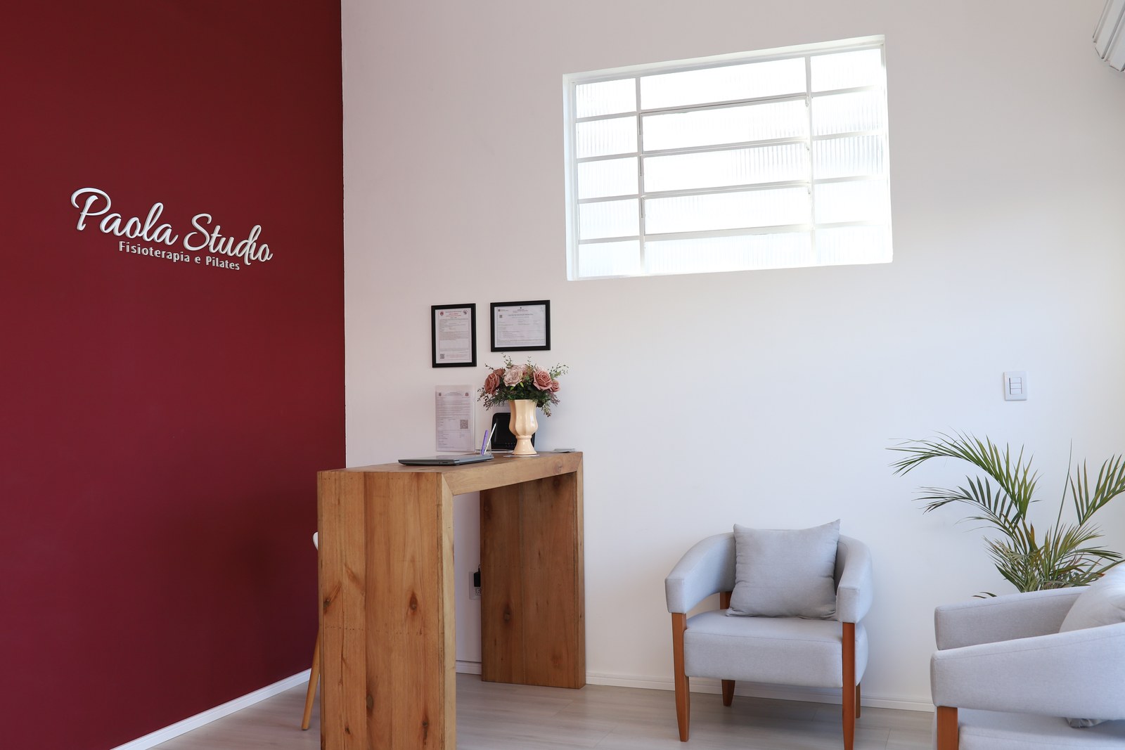 Recepção do Paola Studio com parede marsala e logo da marca